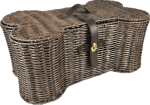 A large woven wicker basket with a lid and leather straps, likely used for storing pet toys.