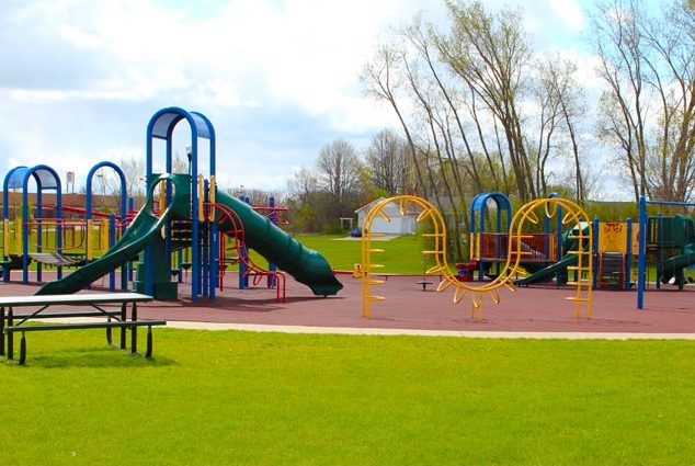 A colorful playground with various equipment and slides on a sunny day with a clear sky.